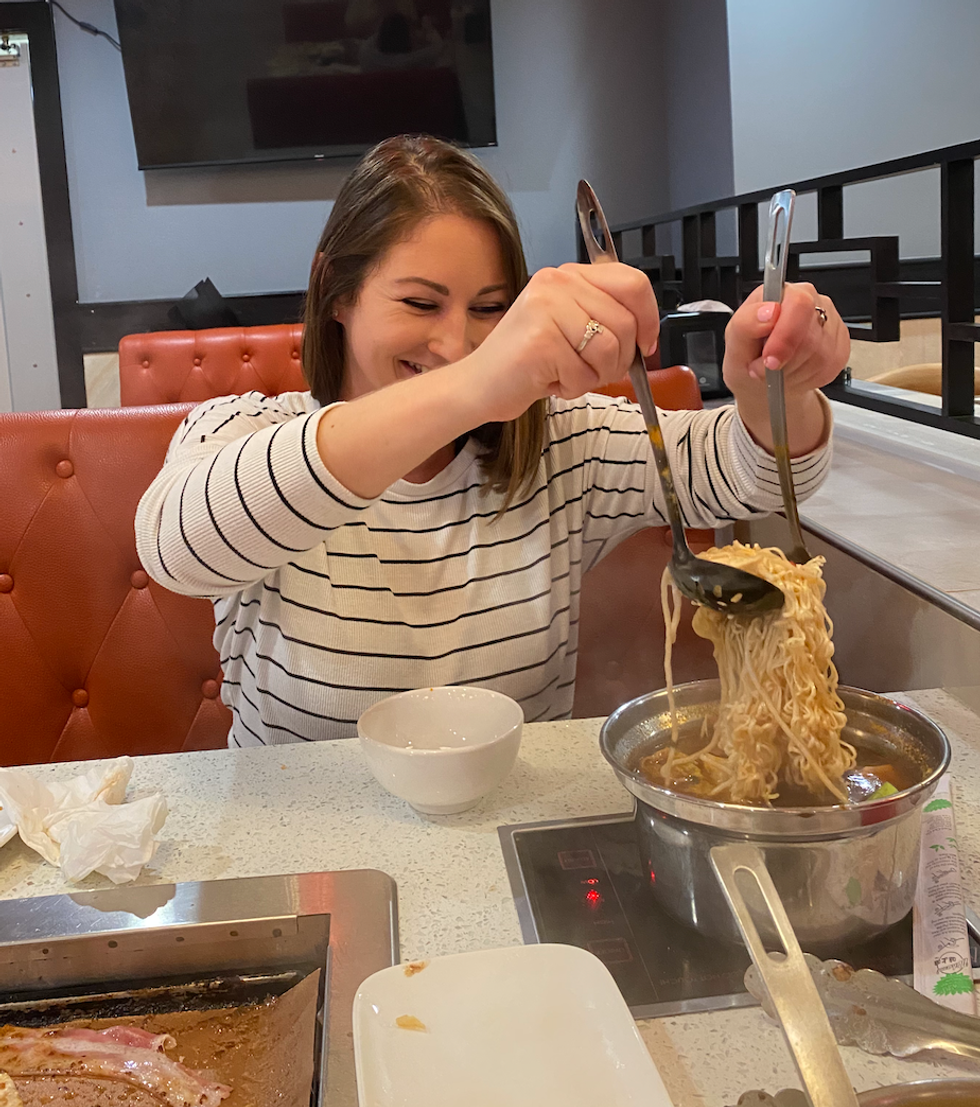 A woman cooking and serving a bowl from the hot pot.