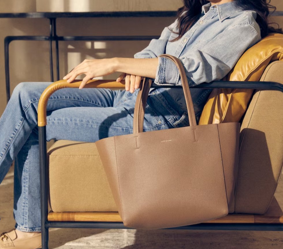 A woman dressed in denim holding a Love & Lore brown tote.