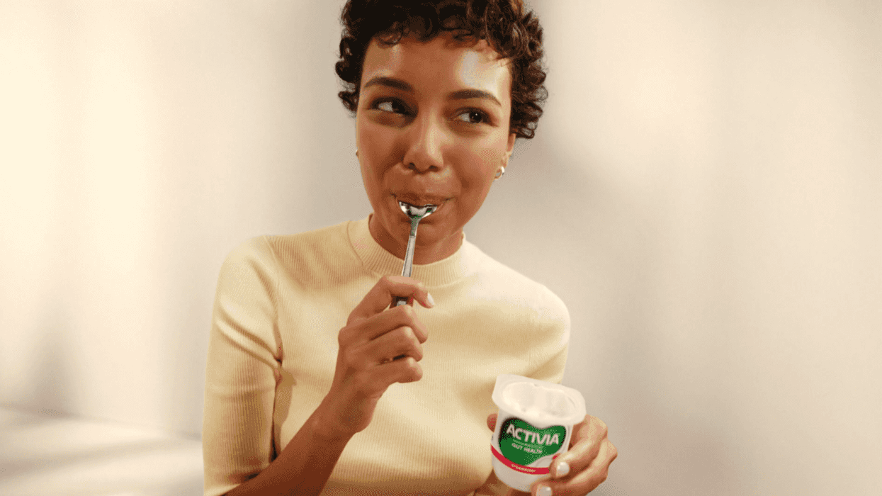 A woman eating from a small tub of Activia yoghurt.