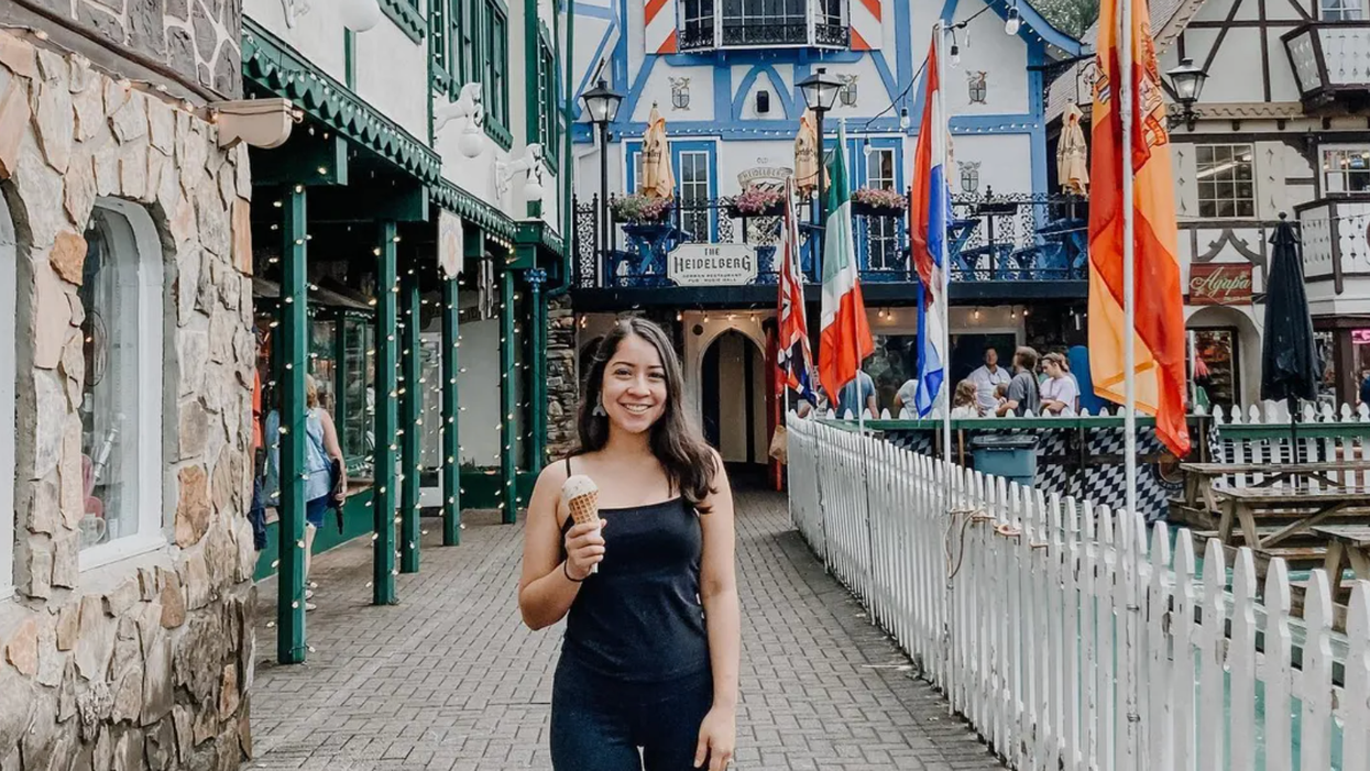 A woman holding an ice cream cone stands in front of German-style buildings.