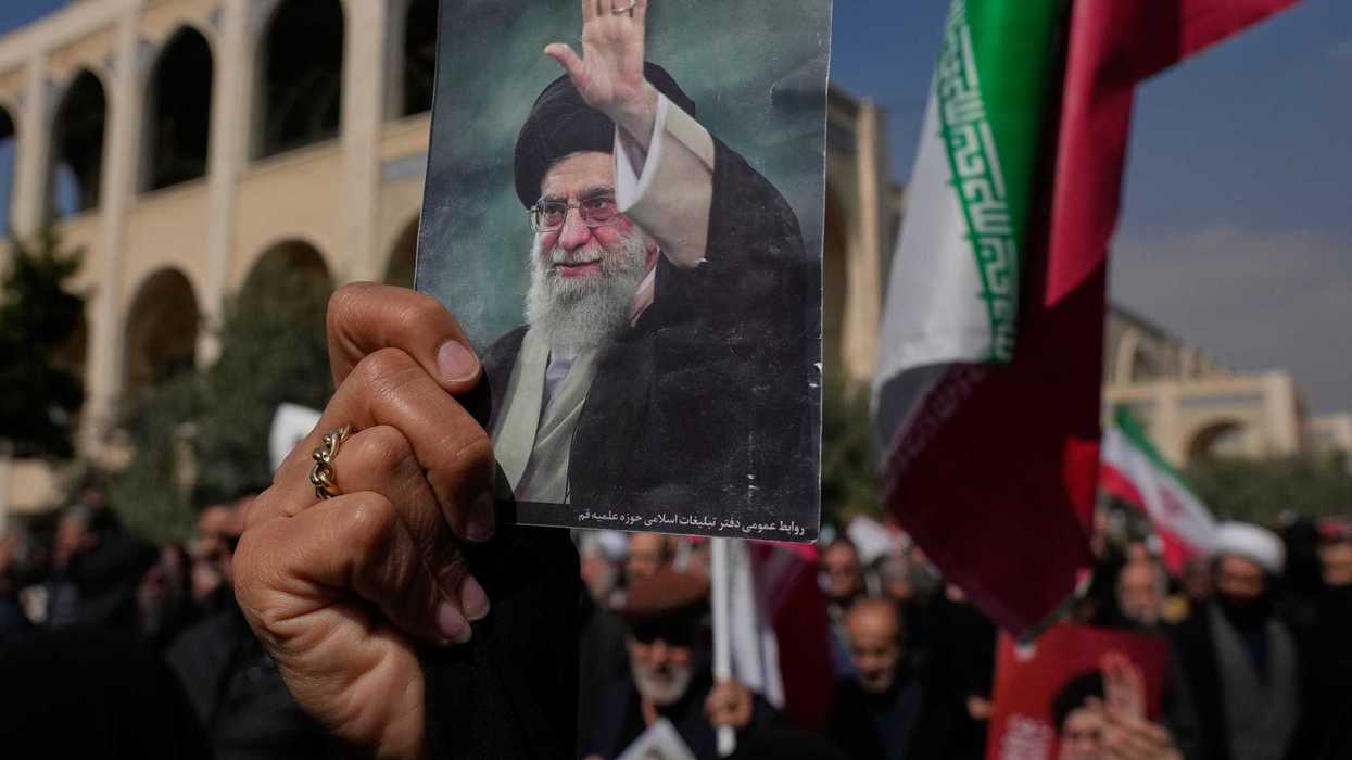 A woman holds up a picture of the late Iranian Supreme Leader Ayatollah Ali Khamenei at a protest.