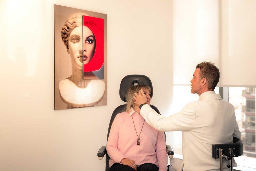 A woman in a pink sweater speaks to Dr. Cory Torgerson about designer facelifts in a clean consultation room.