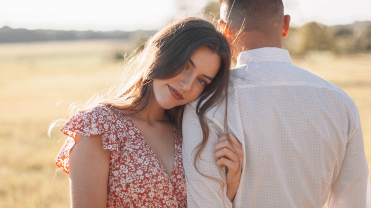 A woman in a red floral dress with a man in a white shirt.