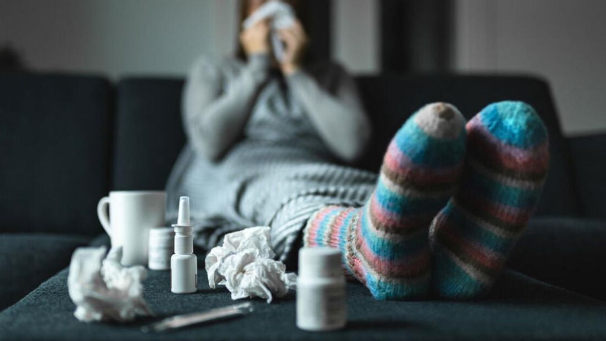 A woman is blowing her nose as she deals with a cold.