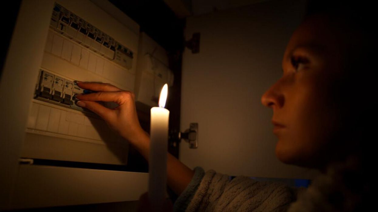 A woman looking at a fuse box during a power outage.