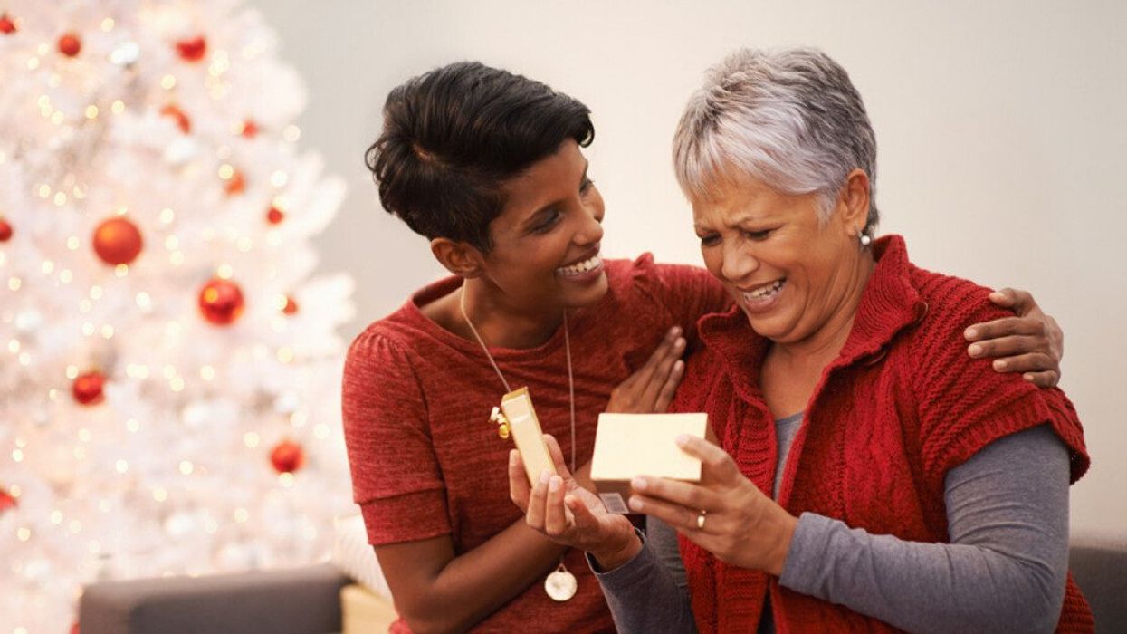 A woman opening a Christmas gift from her daughter.