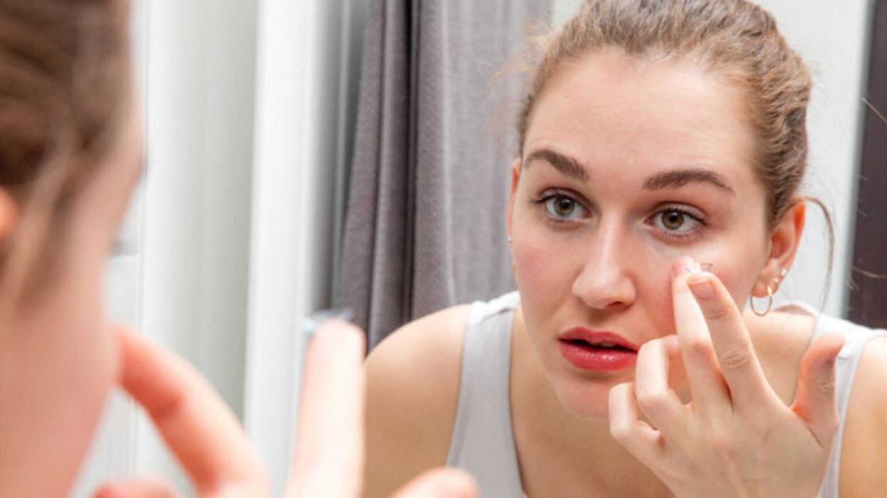 A woman putting a contact lens into her eye.