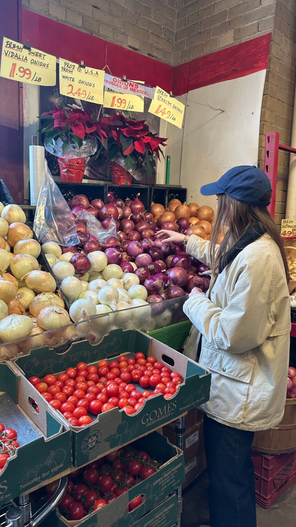 A woman reaching for red onions at a market stall.