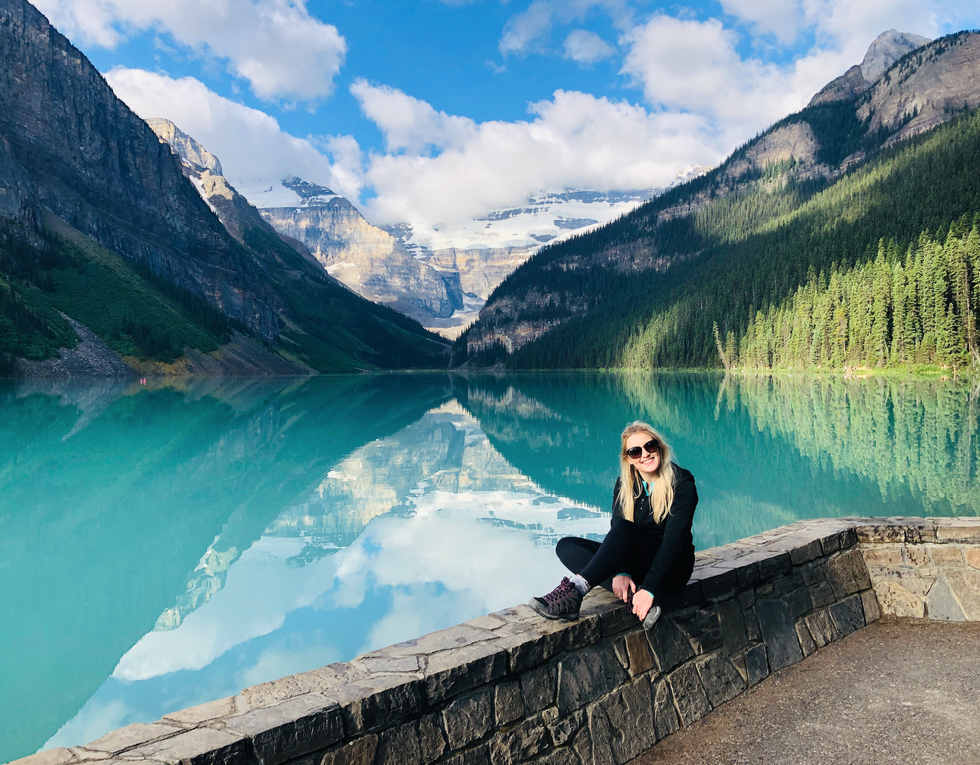 A woman sits beside Lake Louise.