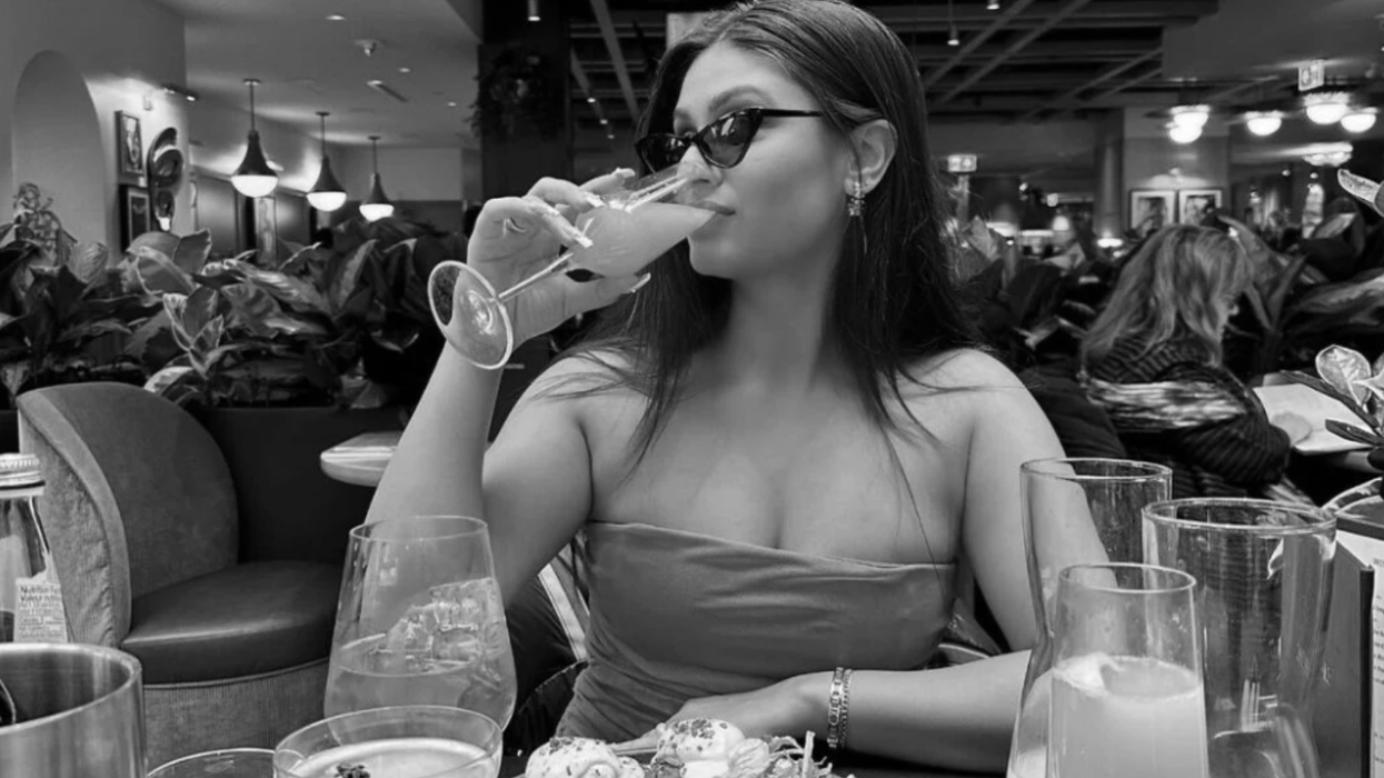 A woman sitting at a table sipping a mimosa.