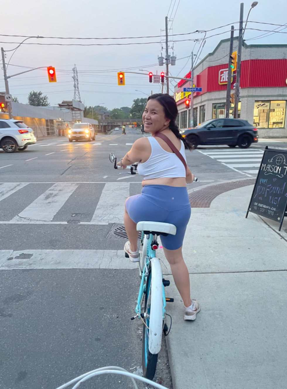 A woman smiles at the camera while riding a bike in Toronto.
