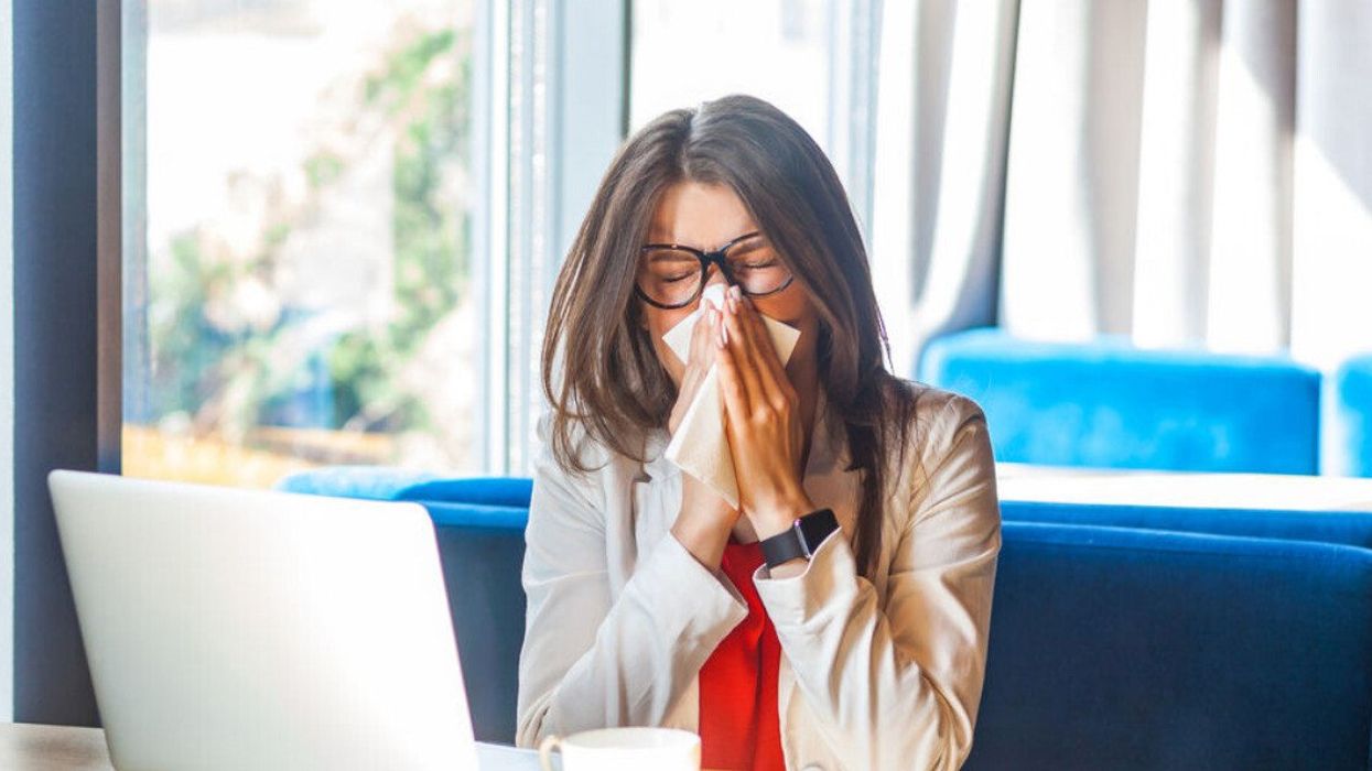 A woman sneezing as she copes with allergy symptoms.