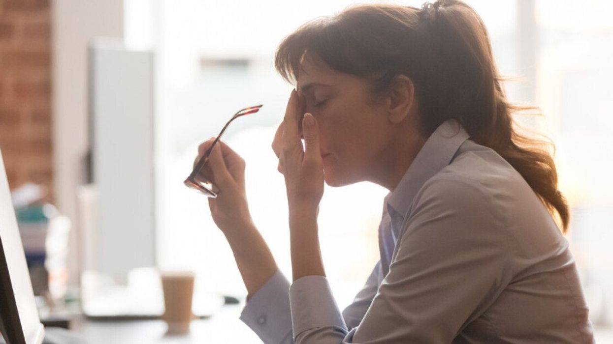 A woman suffering from a migraine at work.
