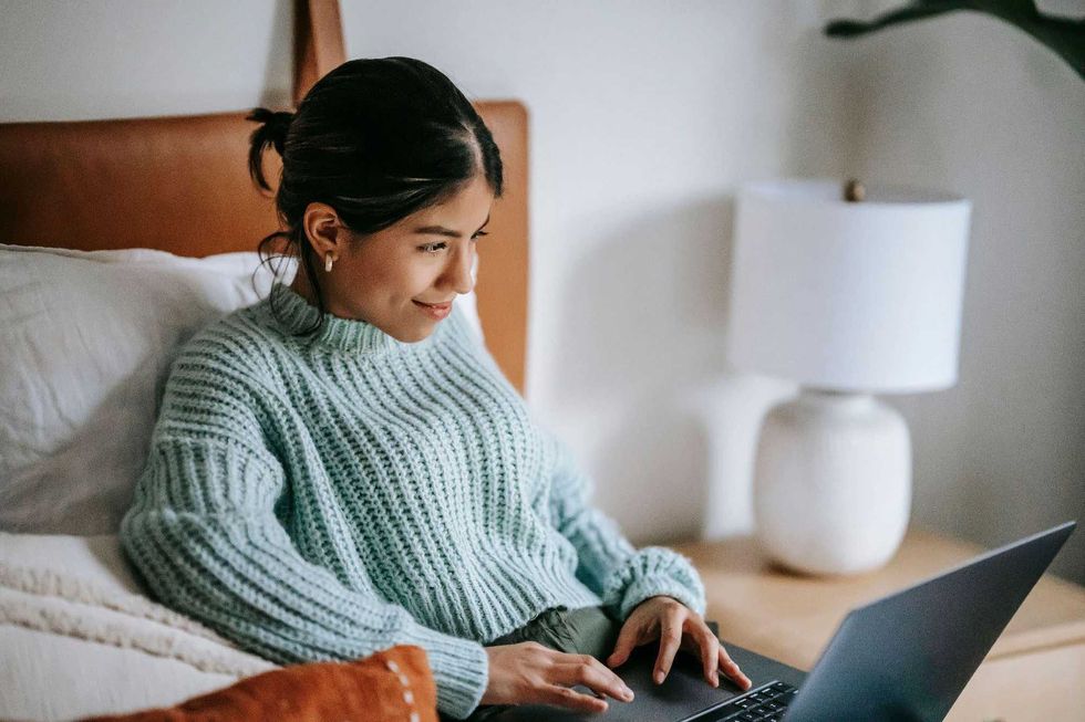 A woman using a laptop in bed.