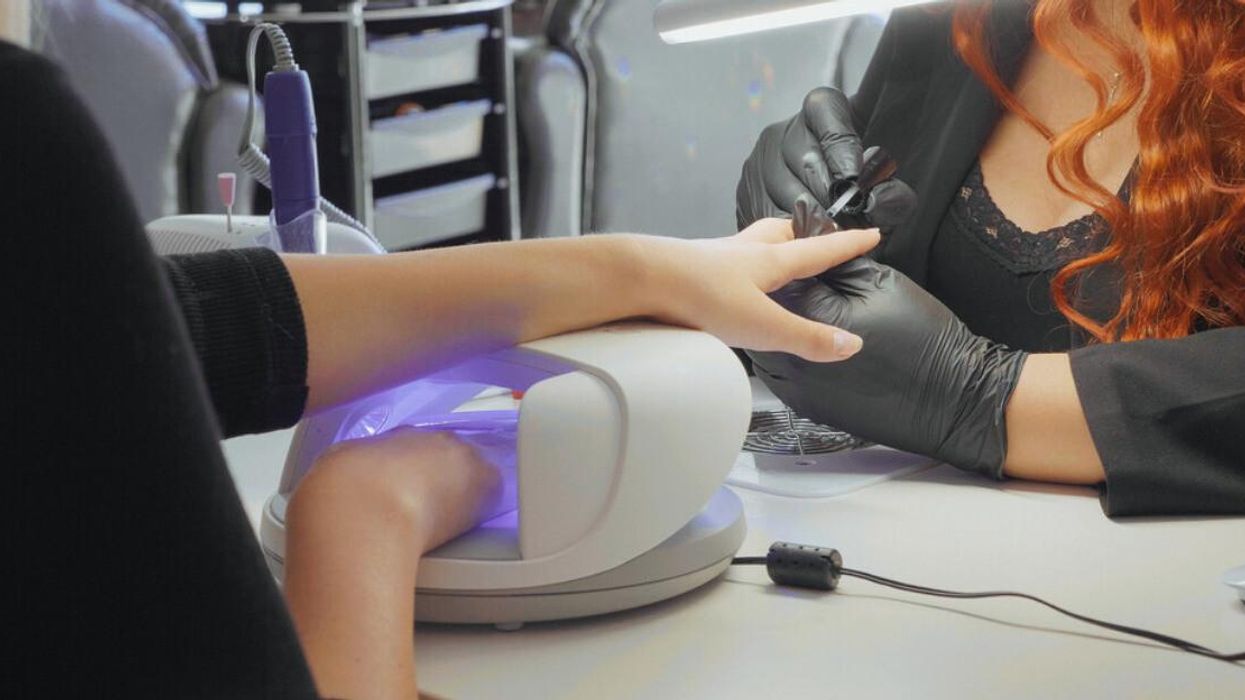 A woman using a UV nail dryer at a salon.