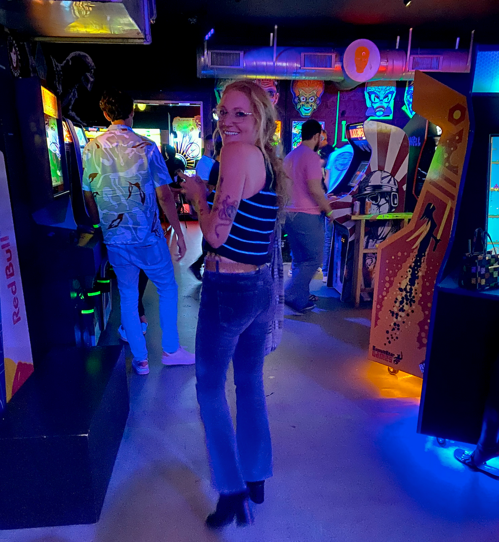 A woman walking into the arcade room.
