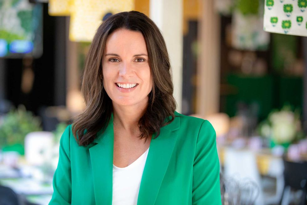 A woman with brown hair wearing a green blazer.