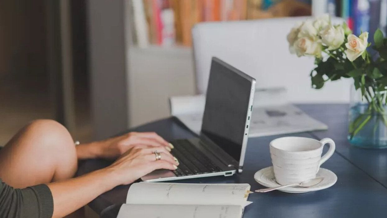 A woman working on a laptop at a kitchen table.