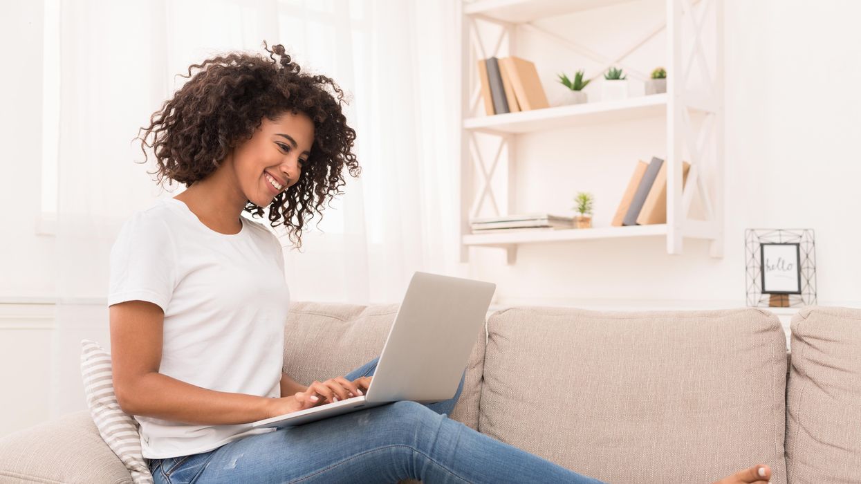 A woman works at her laptop on the couch.
