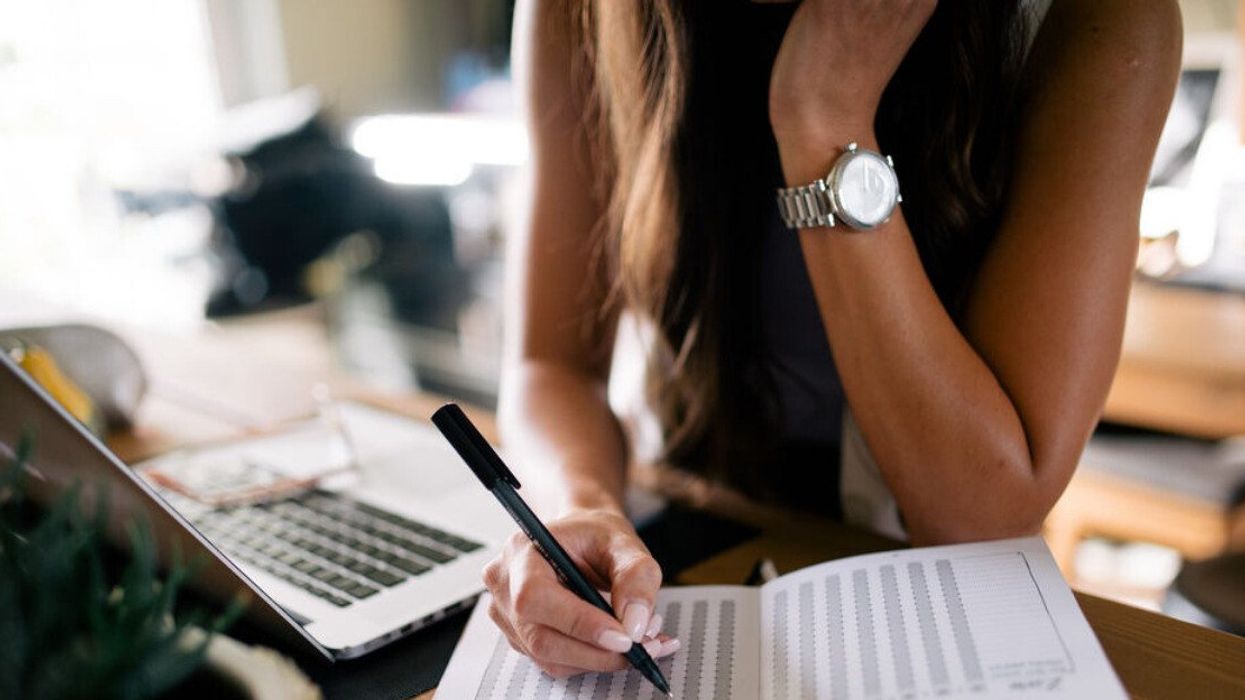 A woman writing notes in a planner.
