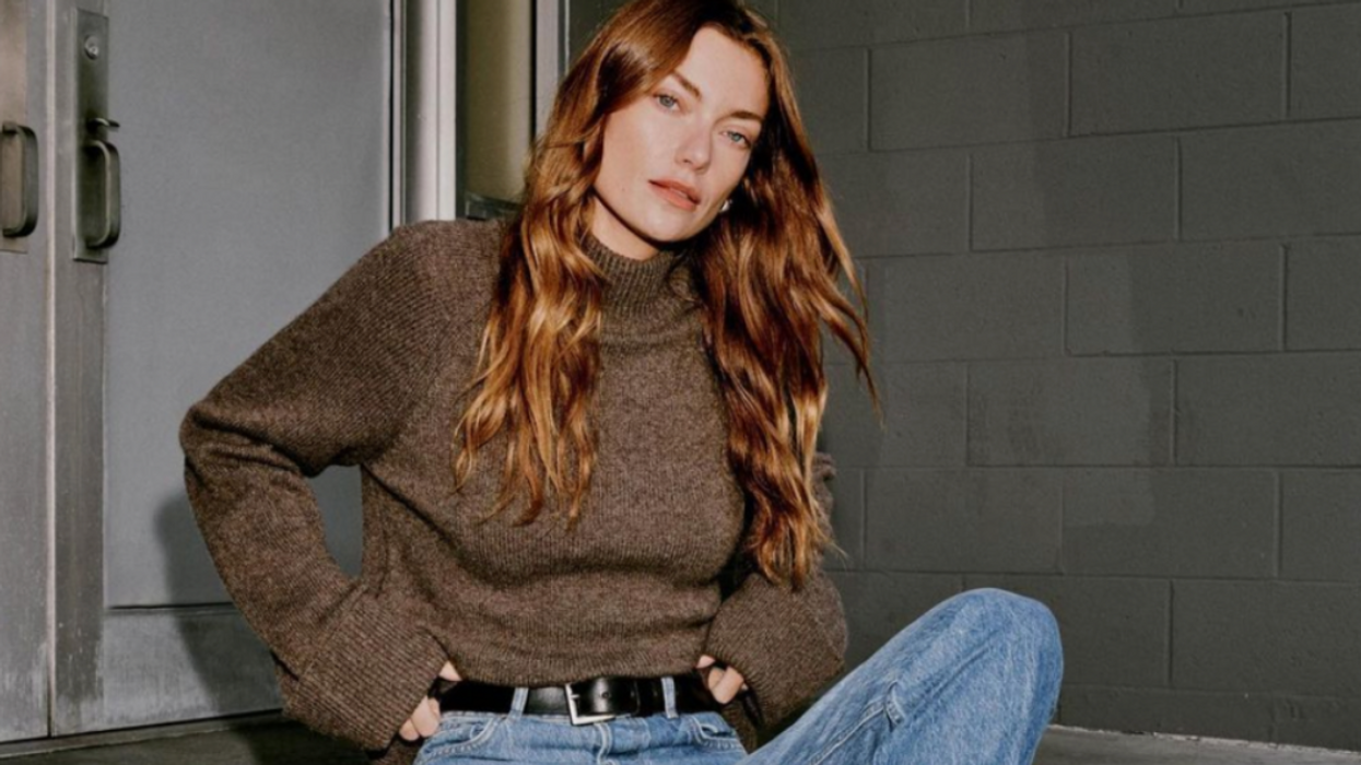 A women wearing a Reformation sweater and jeans.