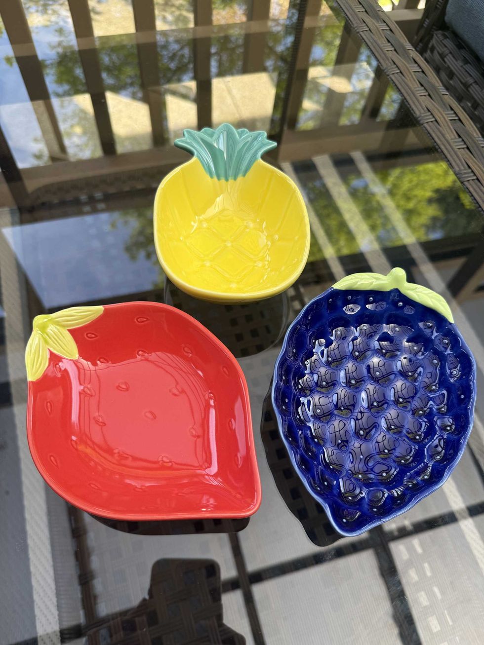 A yellow bowl shaped like a pineapple, a red bowl shaped like a strawberry and a blue bowl shaped like a blackberry.