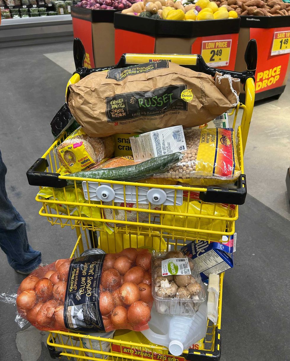 A yellow trolley full of groceries at a grocery store.