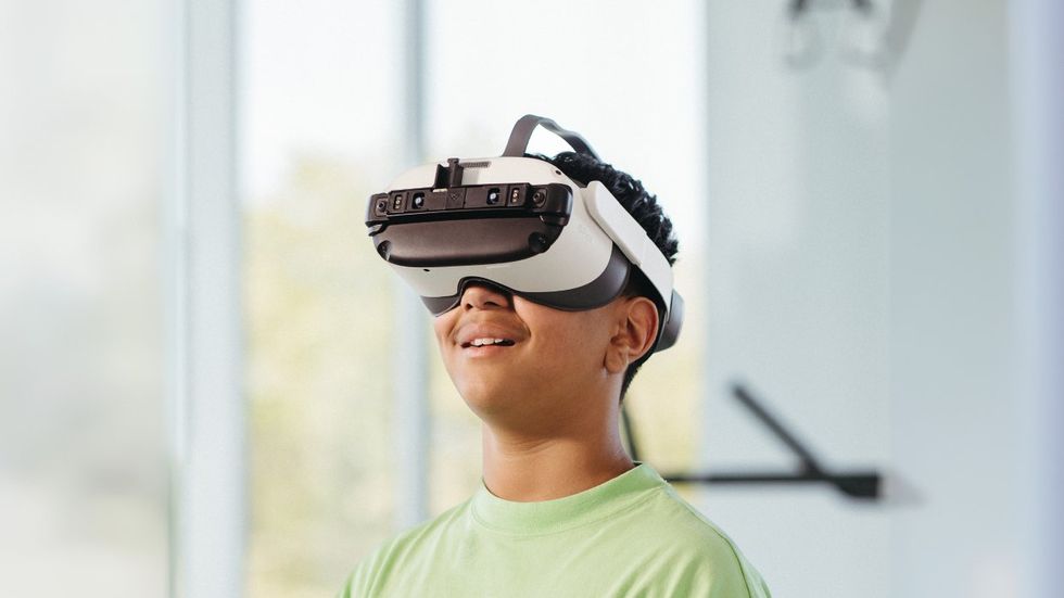 A young man in a green t-shirt wearing a VR headset. 