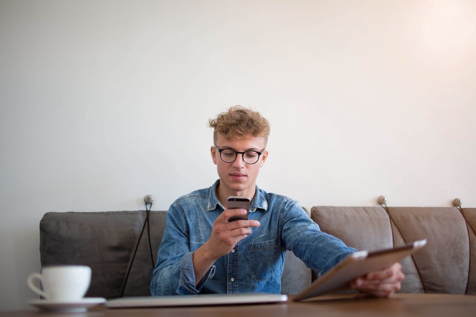 A young person sitting in a cafe reading something on their phone.