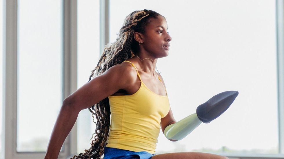 A young woman with a prosthetic arm runs on a treadmill. 