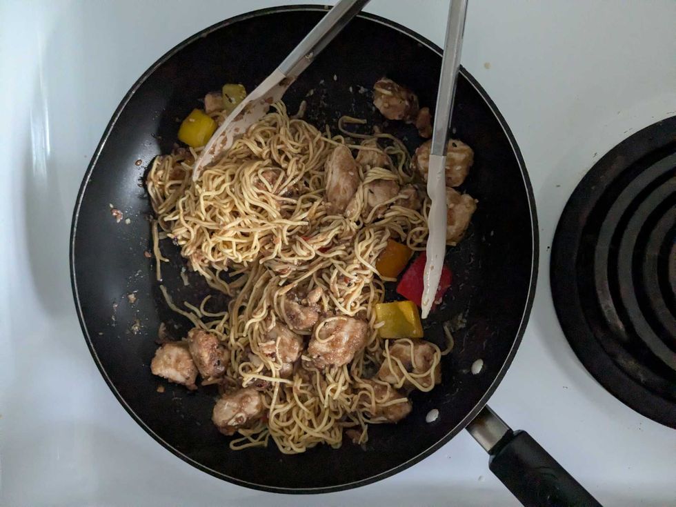 Aerial image of chicken chow mein in a frying pan on a stove