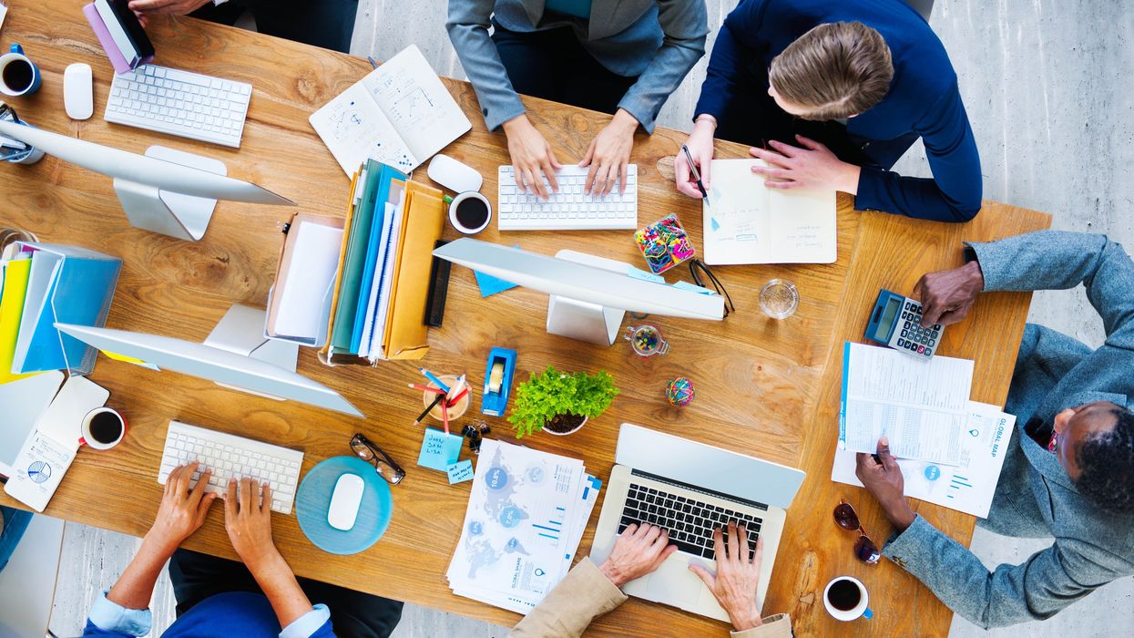 Aerial view of a workstation with people working at computers and on papers.