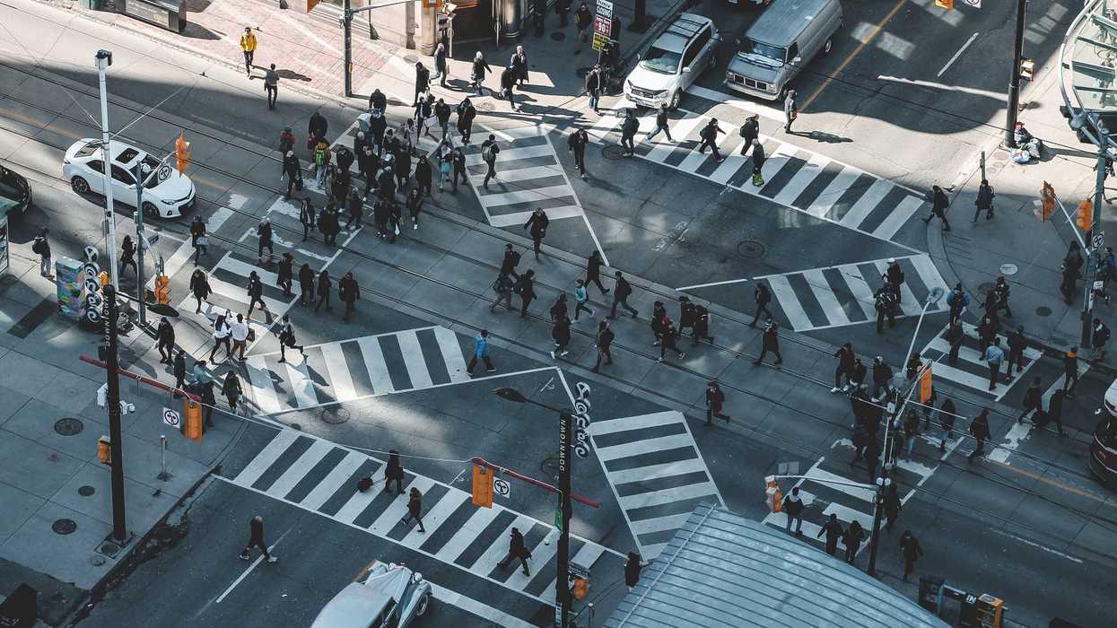 Aerial view of commuters crossing a busy intersection in downtown Toronto.