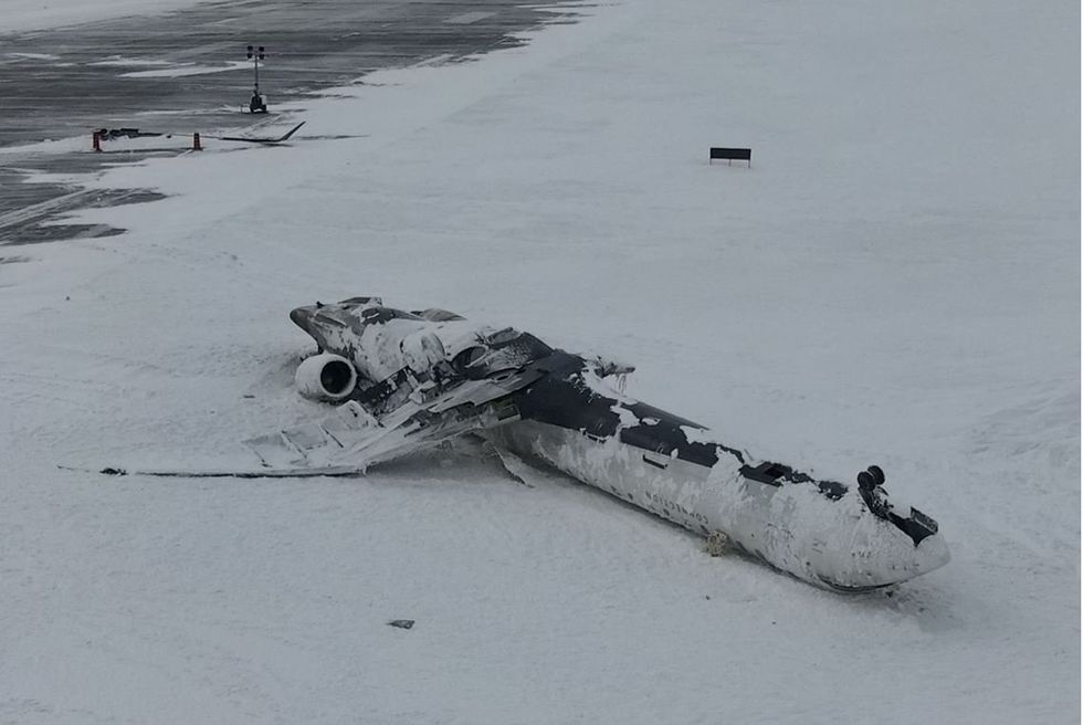 Aerial view of the aircraft wreckage resting on Runway 15L, with the detached wing in the background on Runway 23