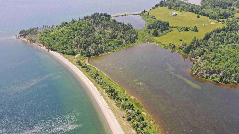 Aerial view of the house for sale and the surrounding property including the lake, the beach and two ponds.