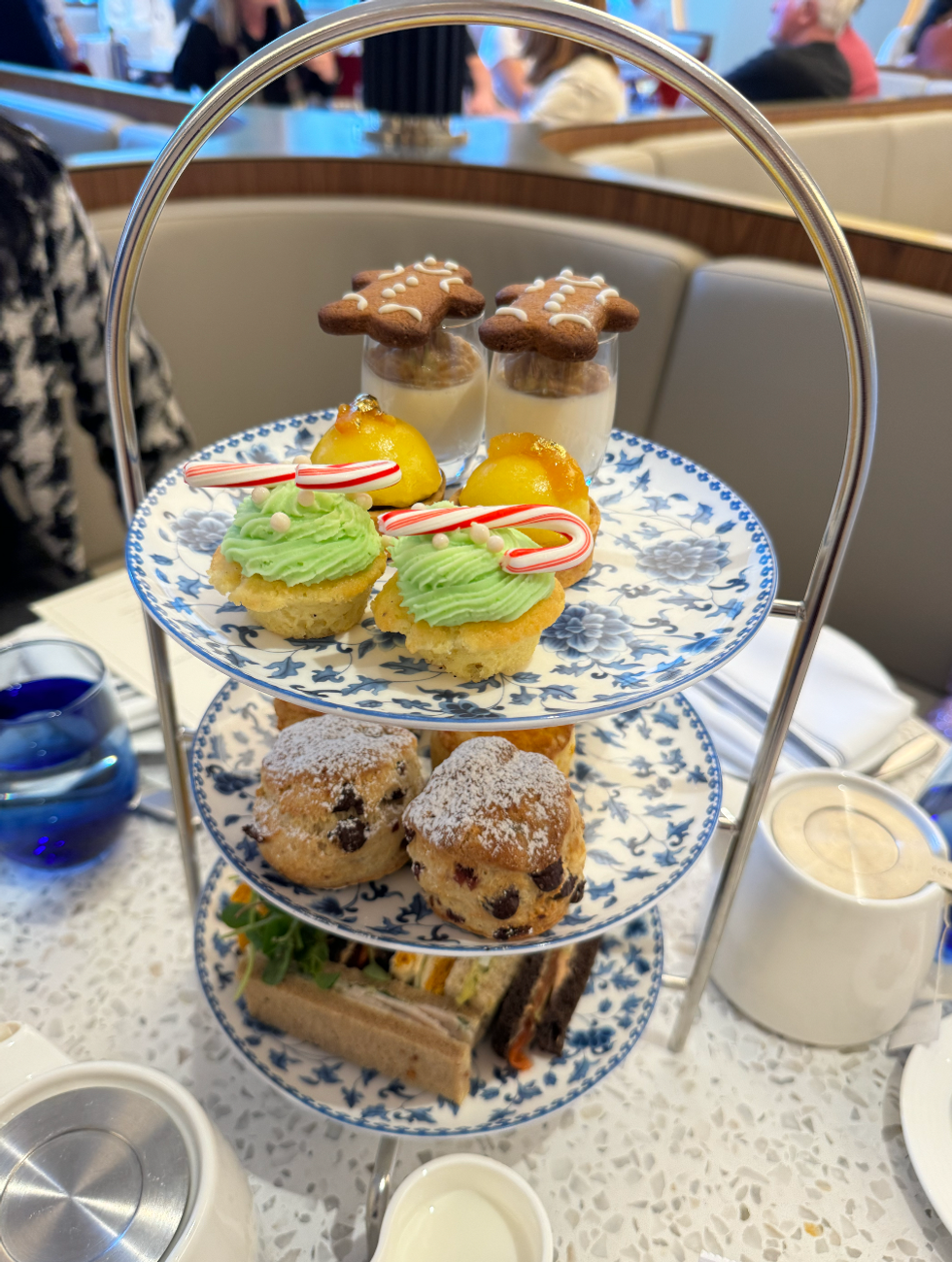 Afternoon tea tower with three tiers including sandwiches, scones and dessert.