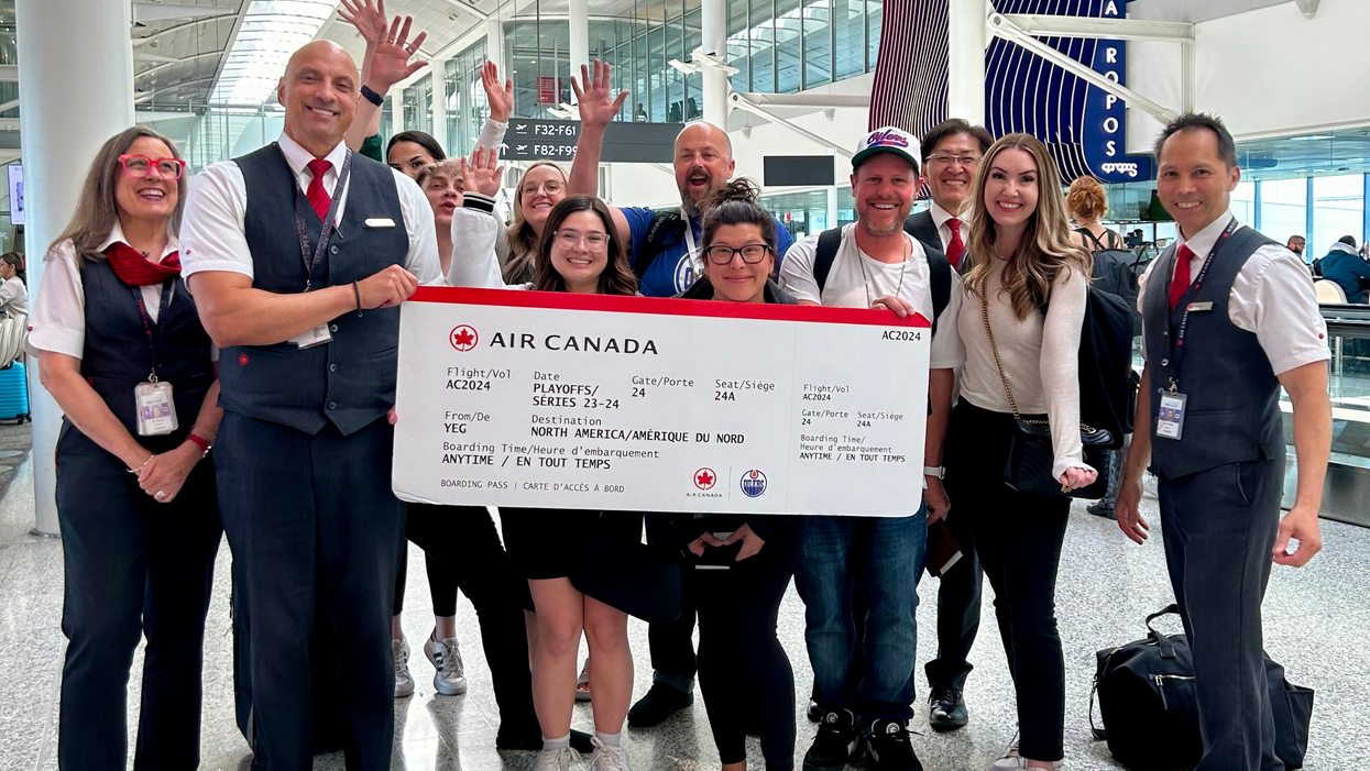 Air Canada Fan Flight winners pose with a giant ticket at the airport before their trip.