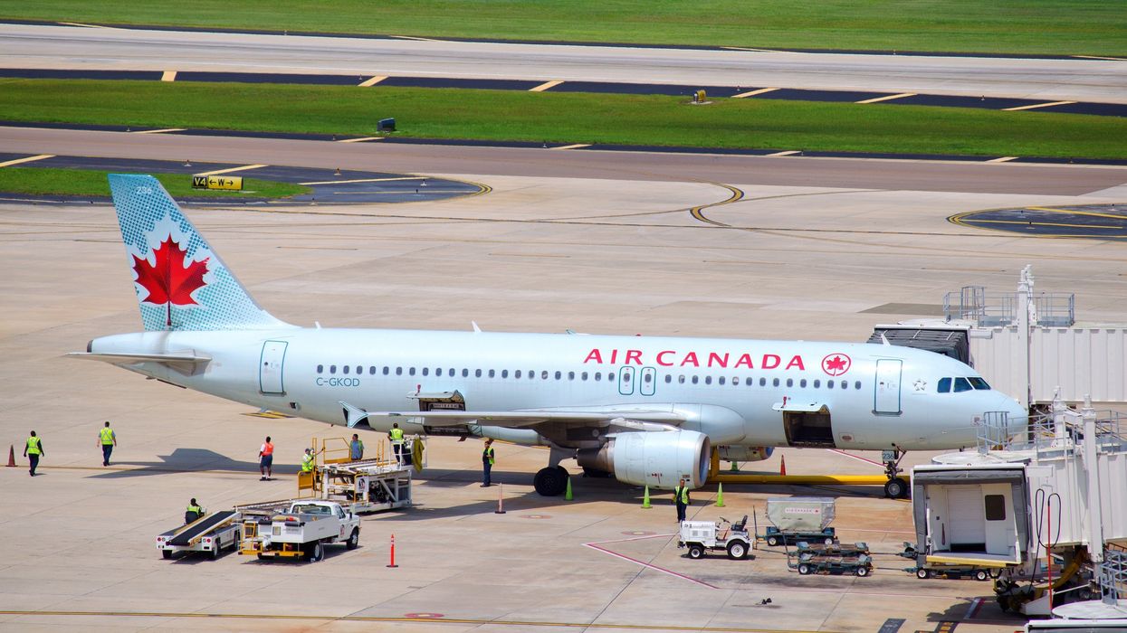 air canada plane on tarmac at airport as grounds crew works on it