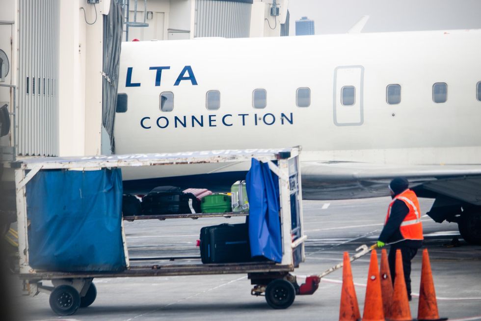 Airline worker loading bags onto a plane at Toronto Pearson Airport.