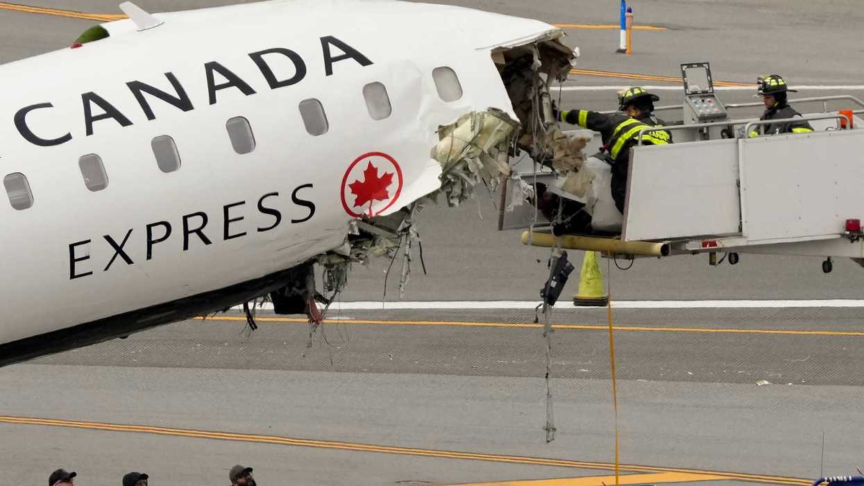 Airport firefighters remove loose debris from the wreckage of an Air Canada Express jet.