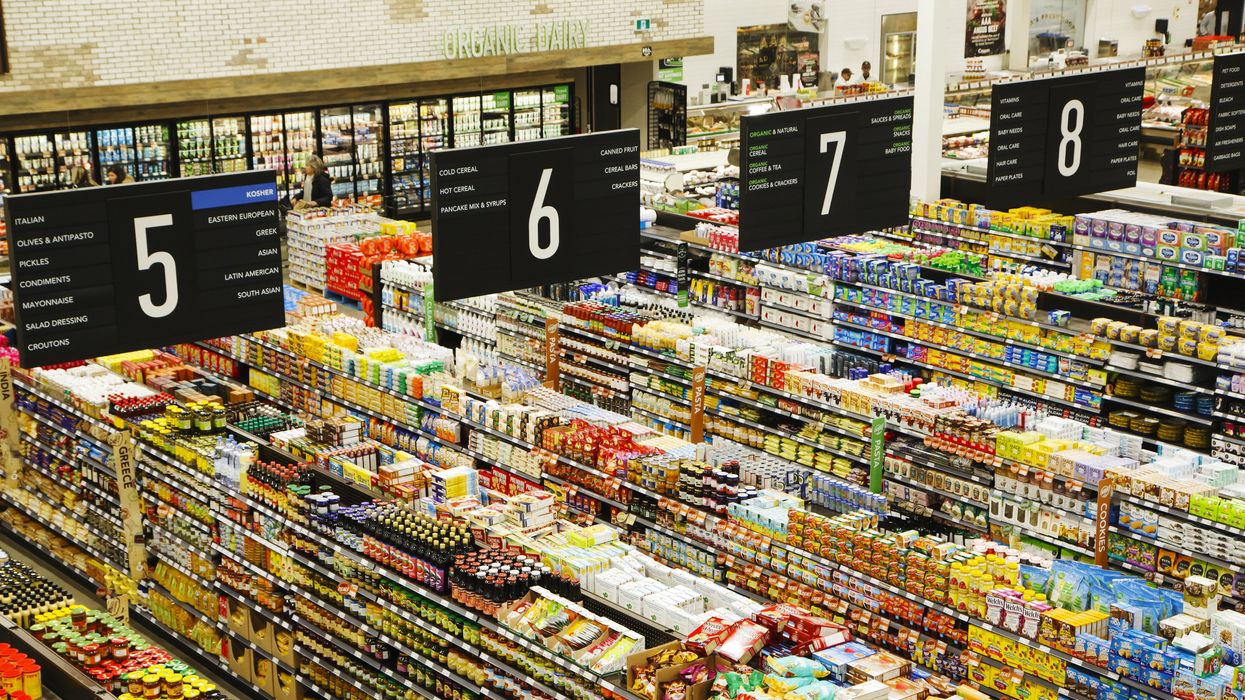 Aisles of groceries in a supermarket with signs saying what food is in the aisle.