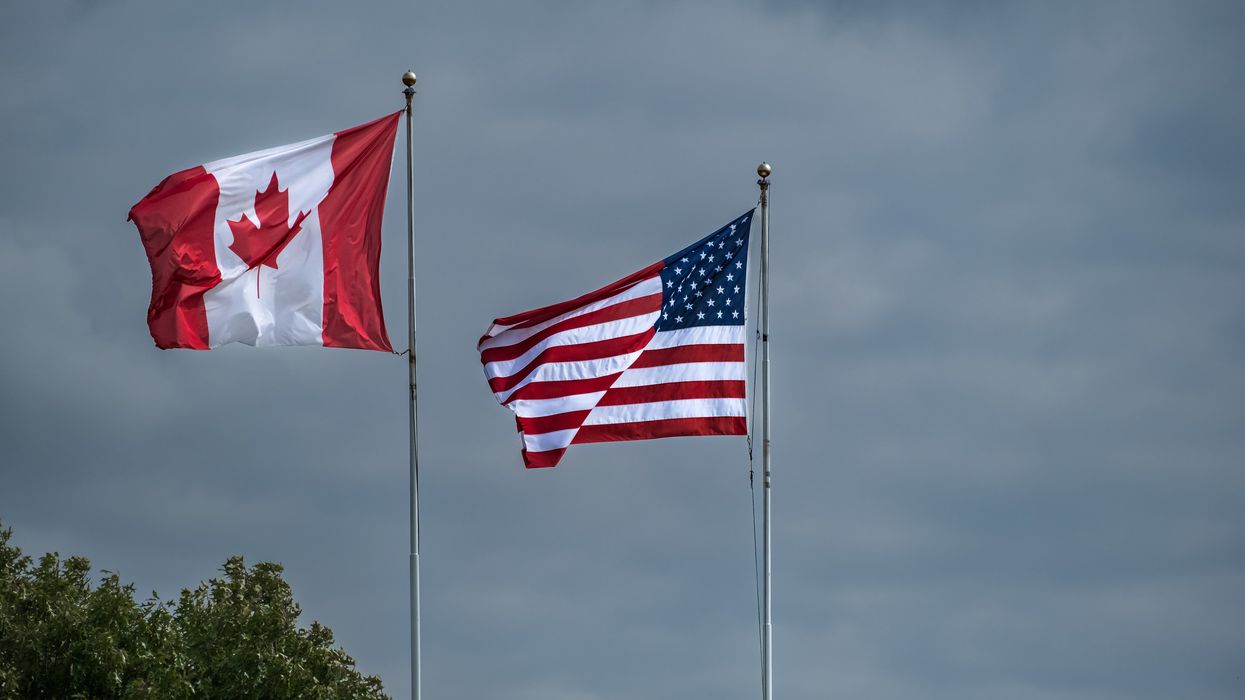 American and Canadian flags flying side by side at the border between the United States and Canada.
