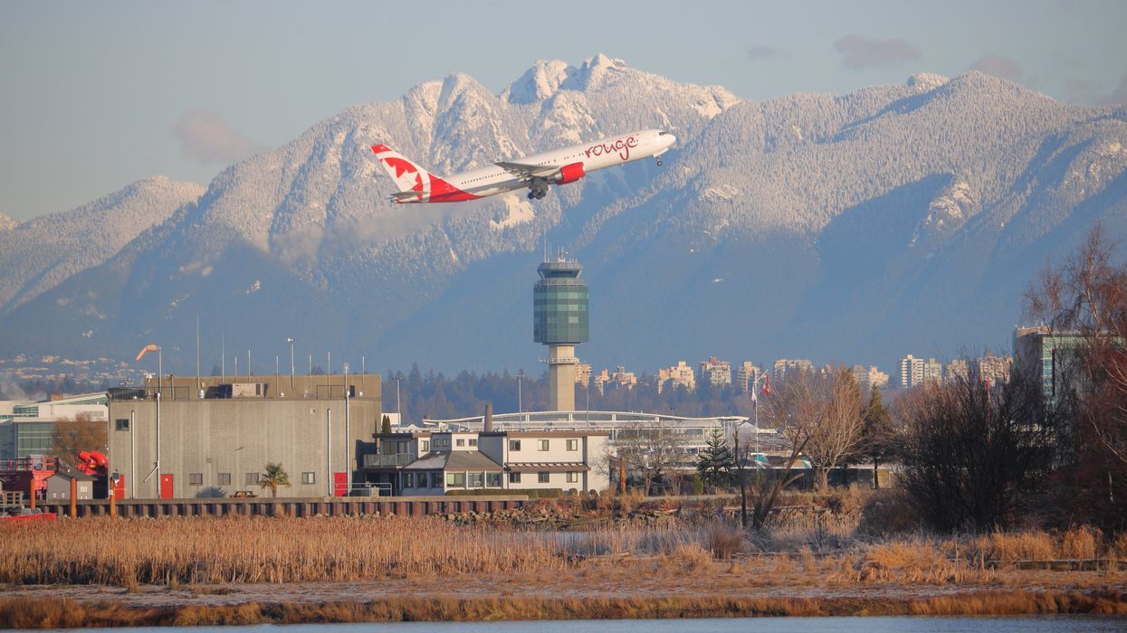 An Air Canada Rouge plane is seen flying over Vancouver airport.
