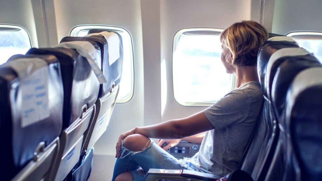 An airline passenger looking out the window during a flight.