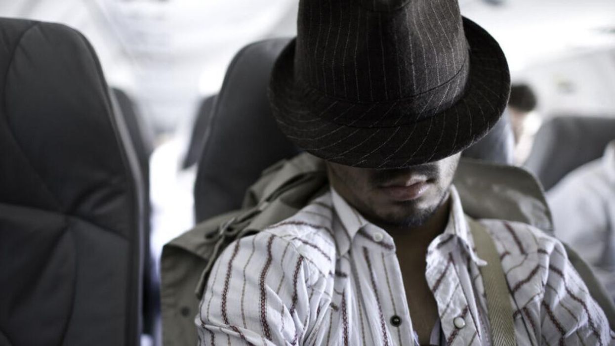 An airline passenger with his hat down on a flight.
