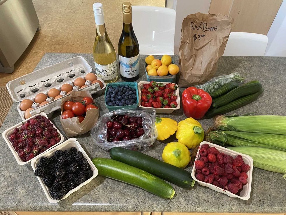 An assortment of fruits, veggies and wine on a kitchen counter.
