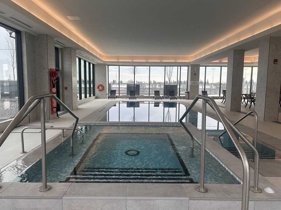 An indoor swimming pool with big windows all around revealing the view.