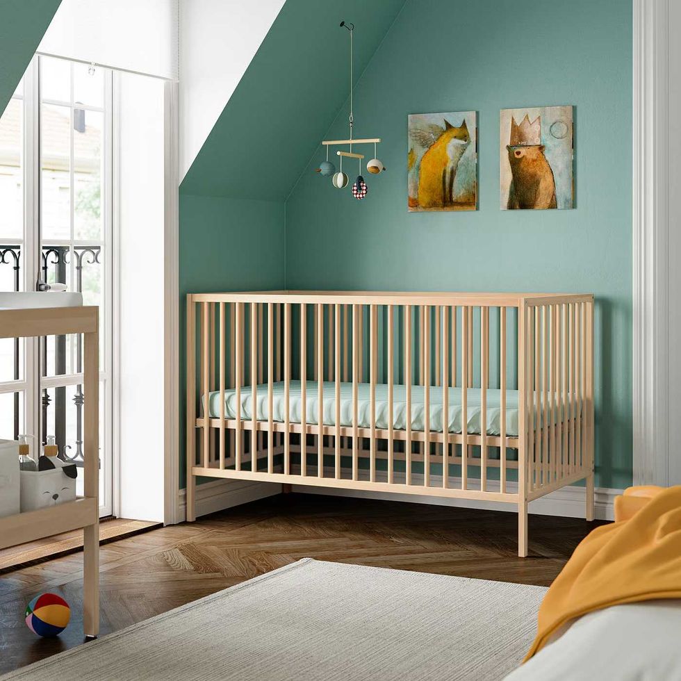 An infant's room featuring a crib made of light beech wood.