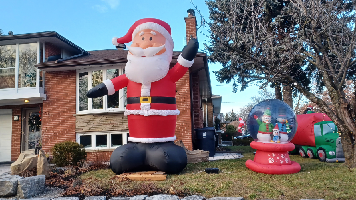 An outdoor Christmas display, with a giant inflatable Santa and snow globe.