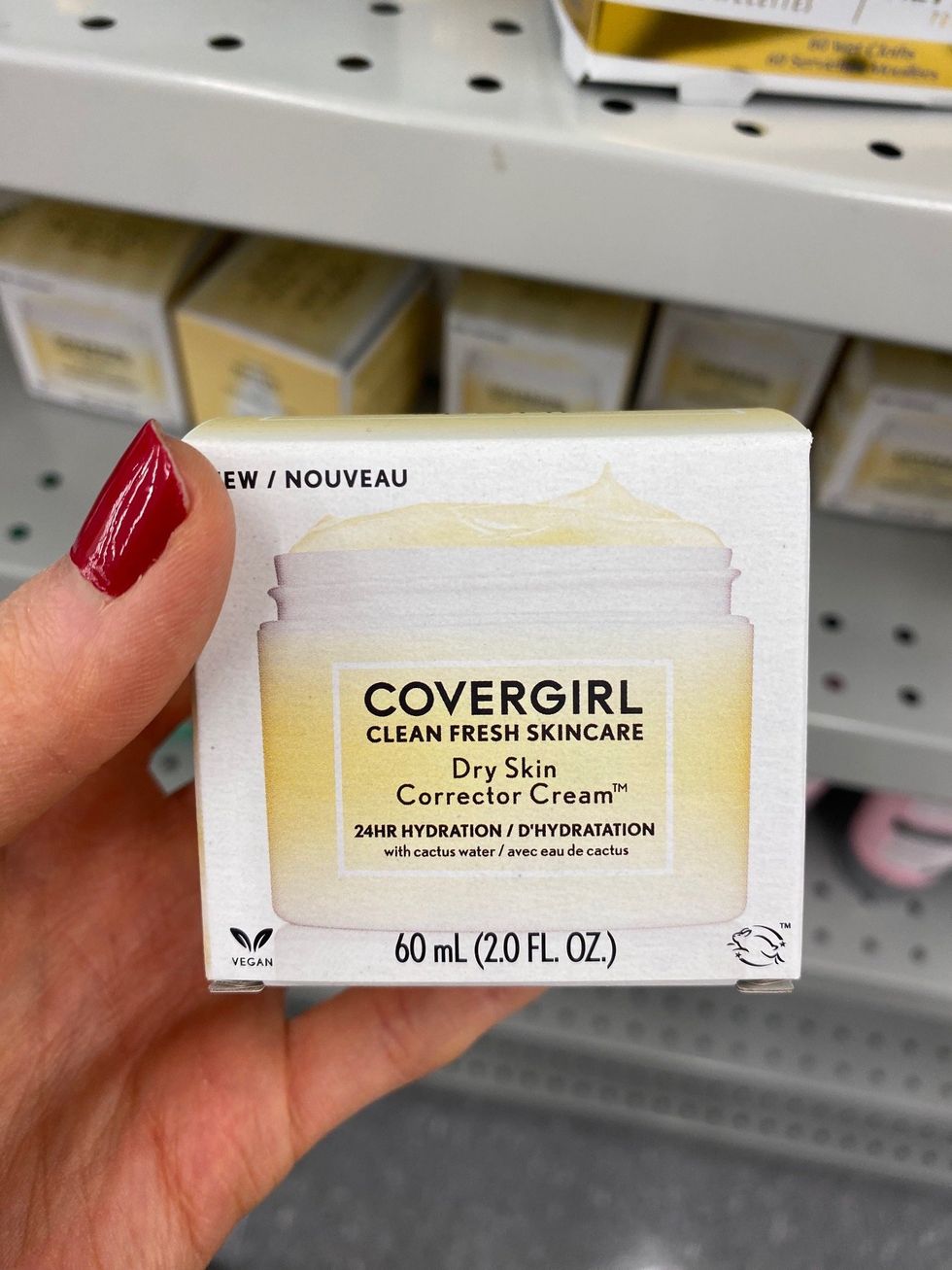 Asymina holding a yellow and white box of CoverGirl moisturizer.